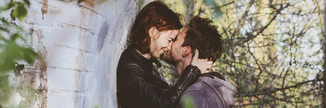 How You Can Explore Sexual Fantasies in a Healthy Way With PTSD photo of a man and a woman kissing under a bridge whle the man holds the woman up