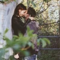 photo of a man and a woman kissing under a bridge whle the man holds the woman up
