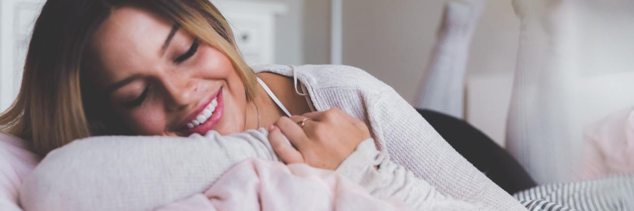 Perfect Gifts for a Highly Sensitive Person photo of smiling woman lying on blankets with her eyes closed