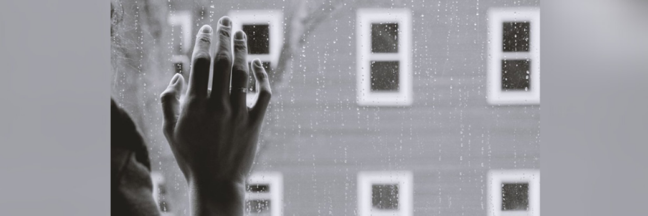 Black and white image of woman's hand on window