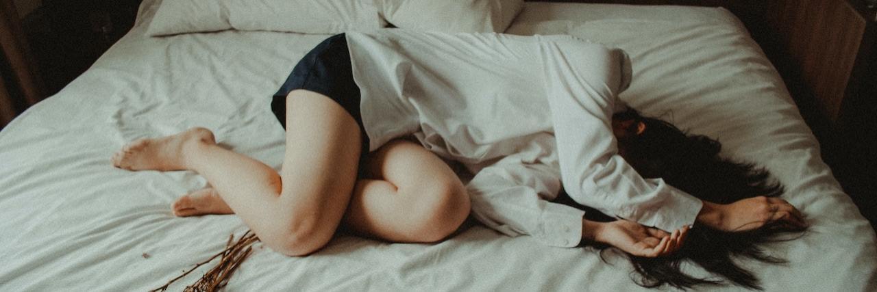 The Unpredictable and Debilitating Nature of Migraine Woman lying on bed with her arm over her face