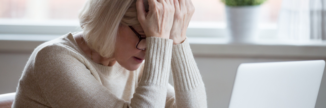 The Mental Health Impact of Staying in an Unhappy Marriage photo of older woman leaning head on hands in front of laptop