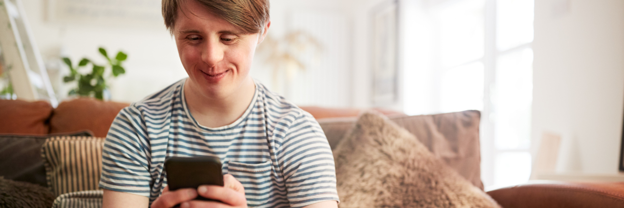 Helpline Launched for People with Developmental Disabilities Person with Down syndrome using a phone