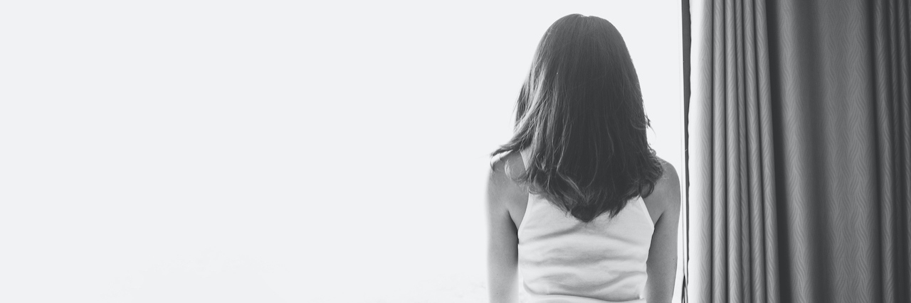 Making Your Way Through Grief by Allowing Yourself to Fully Feel It Black and white photo of the back of a woman sitting on a bed