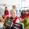 Boy with Down syndrome playing guitar with classmates at school.