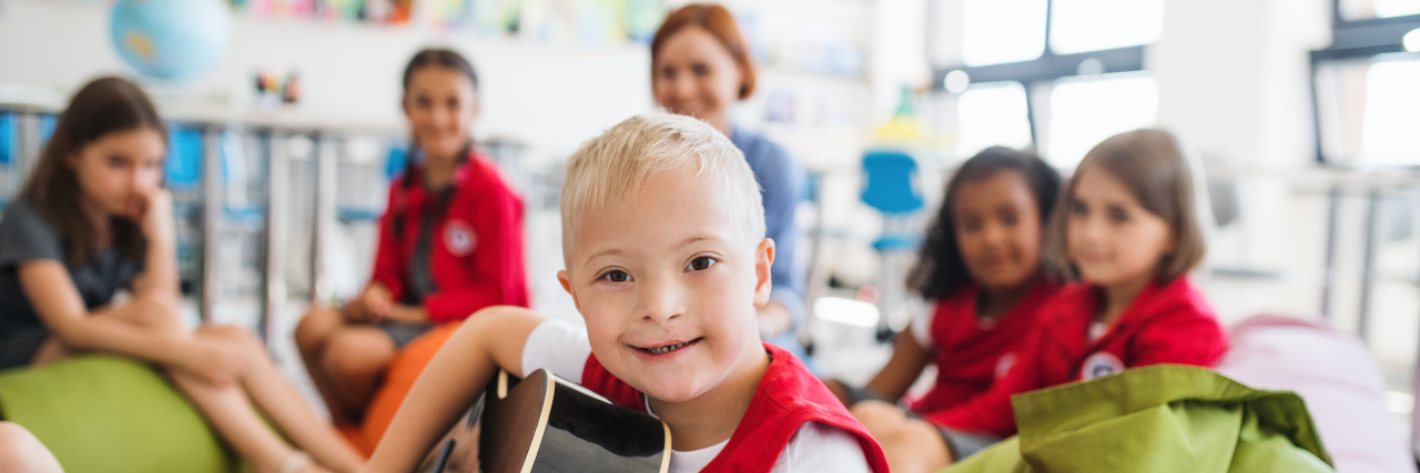 It's Time to Rename Special Education Boy with Down syndrome playing guitar with classmates at school.