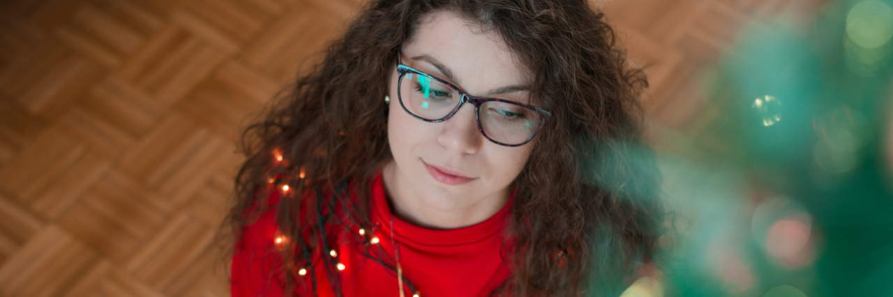 What an Anxious Mom Is Thinking About During the Holidays A woman sitting next to a Christmas tree