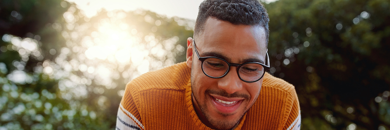 Acknowledging My Depression and the Importance of Others' Support Young Black man sitting outside and smiling at his phone