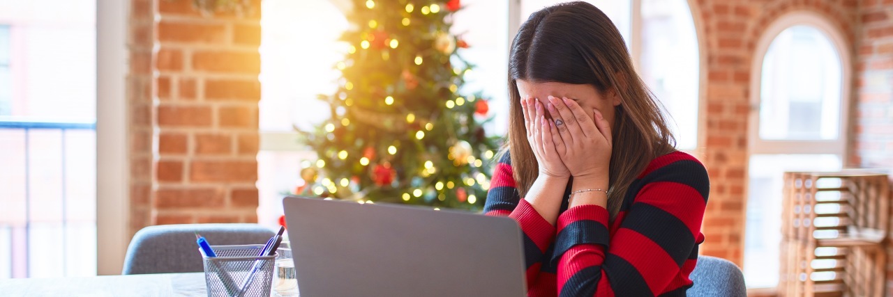 How the Holidays Can Trigger Borderline Personality Disorder Symptoms Woman with hands over her face looking at computer