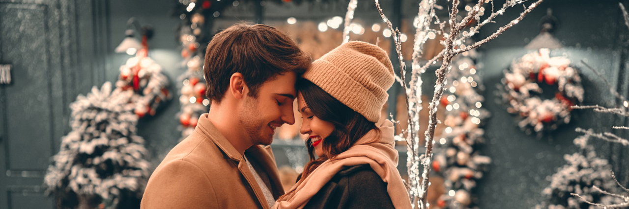 A couple embrace one another in front of christmas decorations