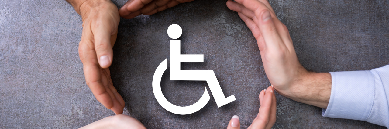 How Society's Obsession With 'Fixing' Disabilities Causes Harm Hands surrounding disability icon.