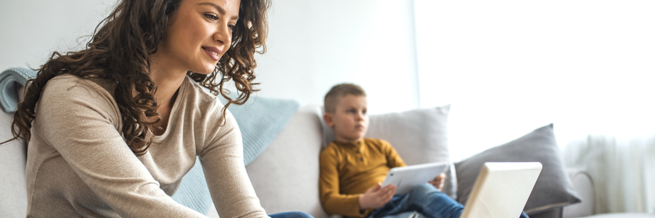 Please Respect Privacy When Posting About Disabled Kids Online Mother using laptop with child in background.