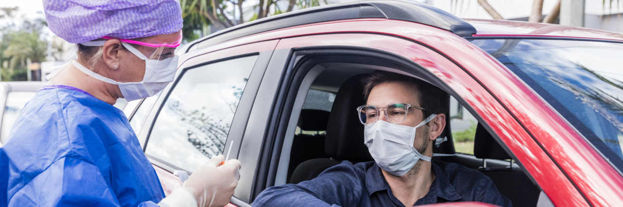 Public Health Officials Say People Don't Believe COVID-19 Danger A doctor in a protective suit taking a nasal swab from a person to test for possible coronavirus infection