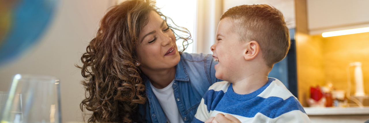 What to Do When People Don't Understand Your Child's Condition mom sitting with her child at a table, laughing with him
