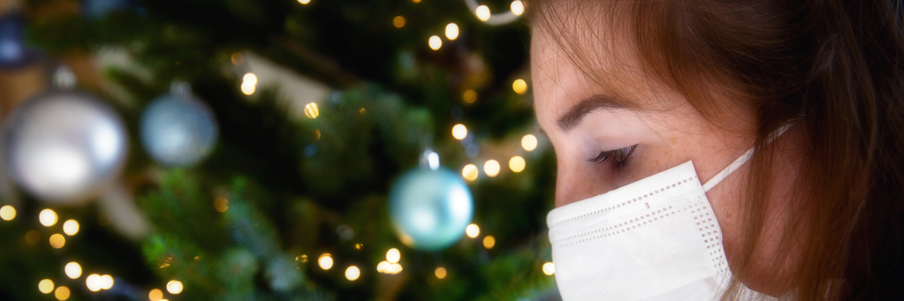 woman in a mask near a christmas tree