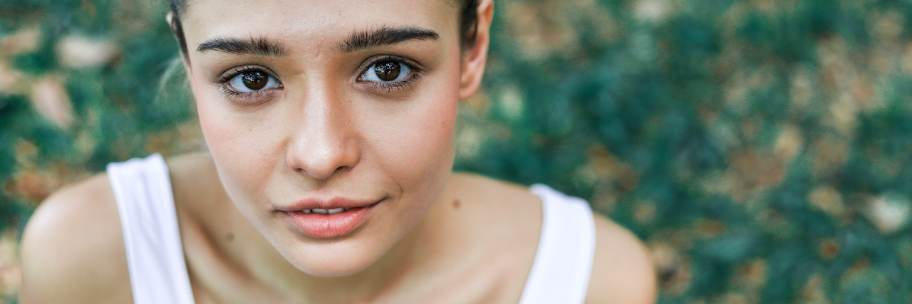 A woman looking serious, sitting in grass