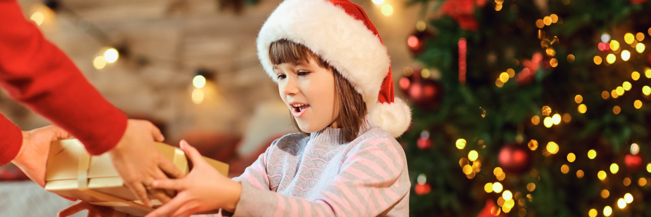 Girl in Santa hat receives a gift at Christmas.