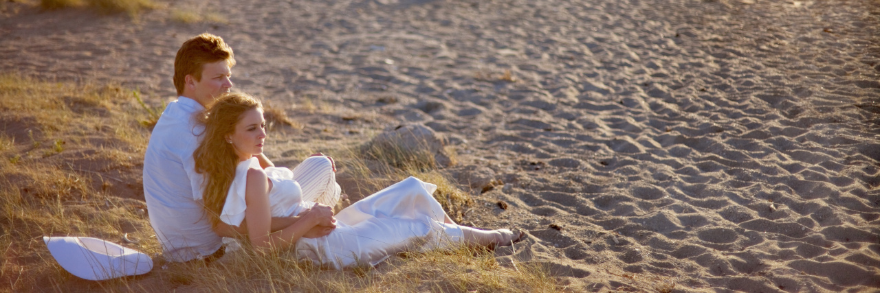 Creating Intimacy When Your Partner Has Chronic Pain Couple sitting on the beach.