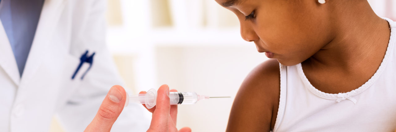 pediatrician injecting vaccine in young girl's arm