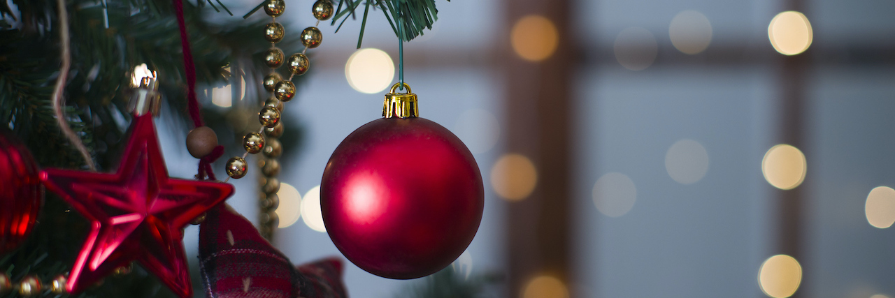 Shiny Christmas red ball hanging on pine branches with festive background