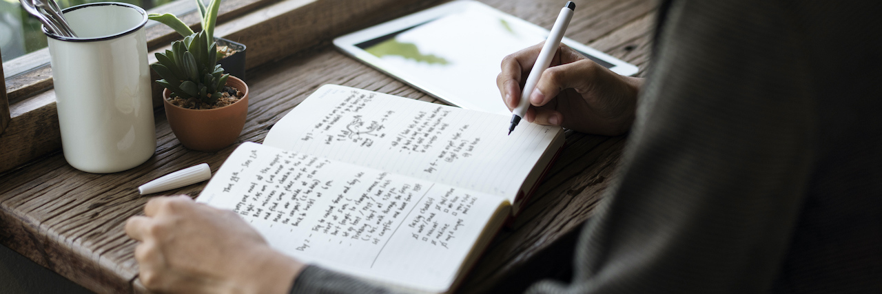 Finding an Old Journal That Details Struggles With an Eating Disorder A woman sitting at a table, writing in a journal