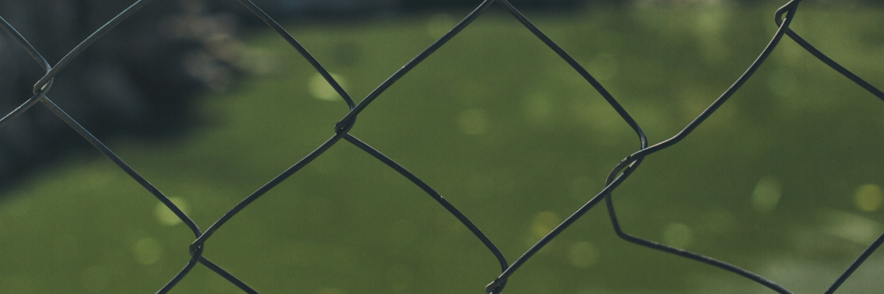 The Summer I Had Celiac Disease But Nobody Knew a steel fence with a field in the background