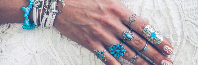 Woman's hand with lots of boho style jewelry, rings and bracelets.