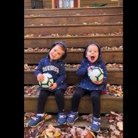 twin toddler girls sitting on steps laughing with balls