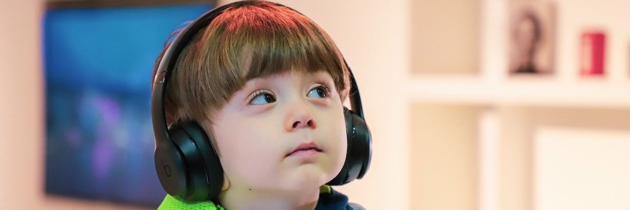 Young boy wears headphones in a living room