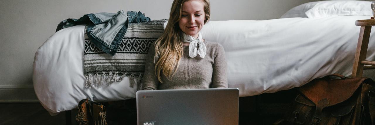 The 5 Best Mental Health YouTube Channels photo of a woman sitting on the floor near a bed with a laptop on her legs