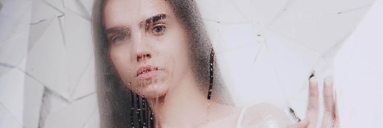 Identifying My 'Stuck Points' Is Helping Me Process My Trauma photo of woman holding up hands in foggy image with fractured glass effect