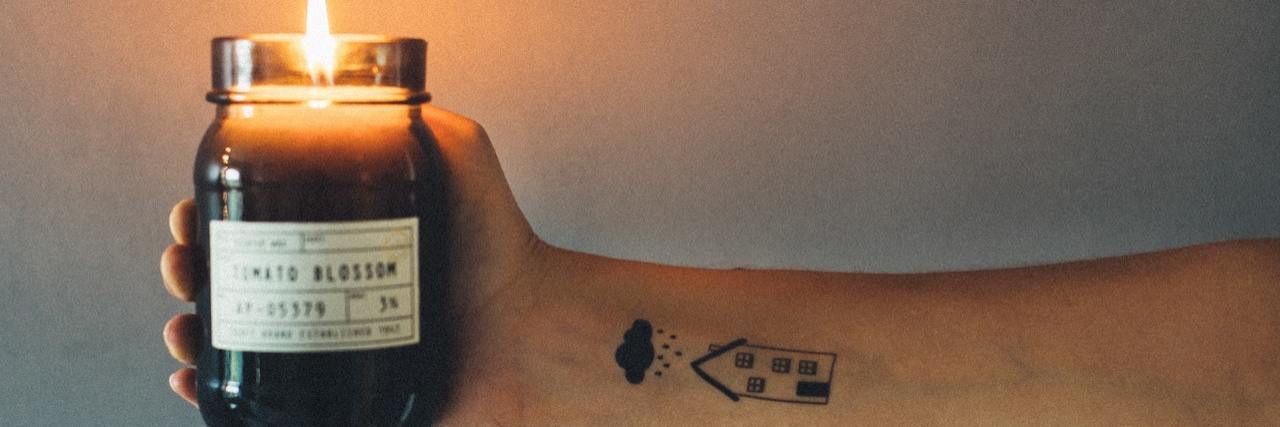 Not Just a Statistic: When a Sibling Dies of Suicide A woman holding out a handle. On her wrist is a tattoo of a raincloud over a house