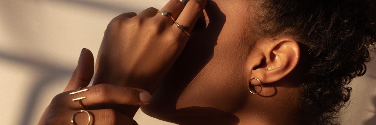 How I'm Beginning to Heal My Relationship With Food A woman in shadow, covering her face with her hand