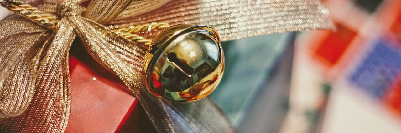 What to Consider Before Traveling Home for the Holidays During COVID Wrapped gift with a gold bow and large jingle bell