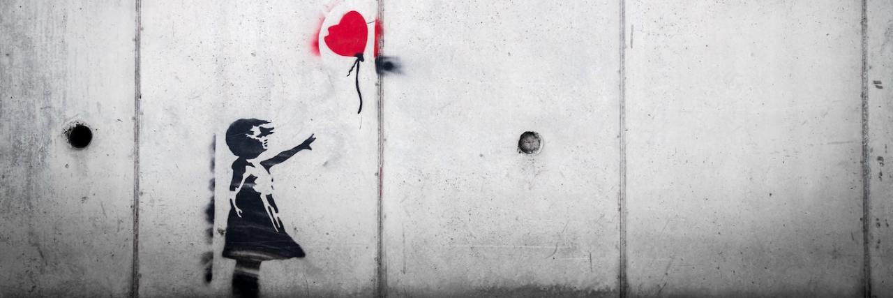 A mural of a young girl reaching for a red heart-shaped balloon.