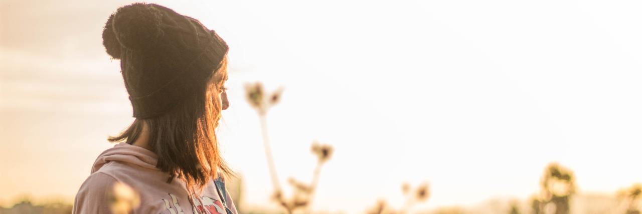 10 Ways I'm Overcoming My PTSD and Trauma young girl in a black beanie standing out in a field during spring