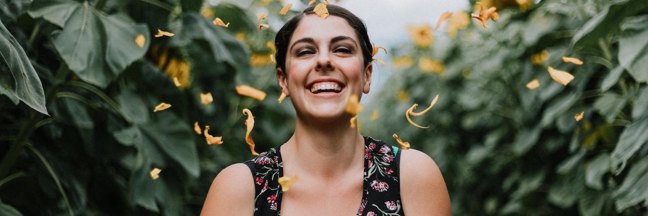 A woman smiling with flower pedals around her