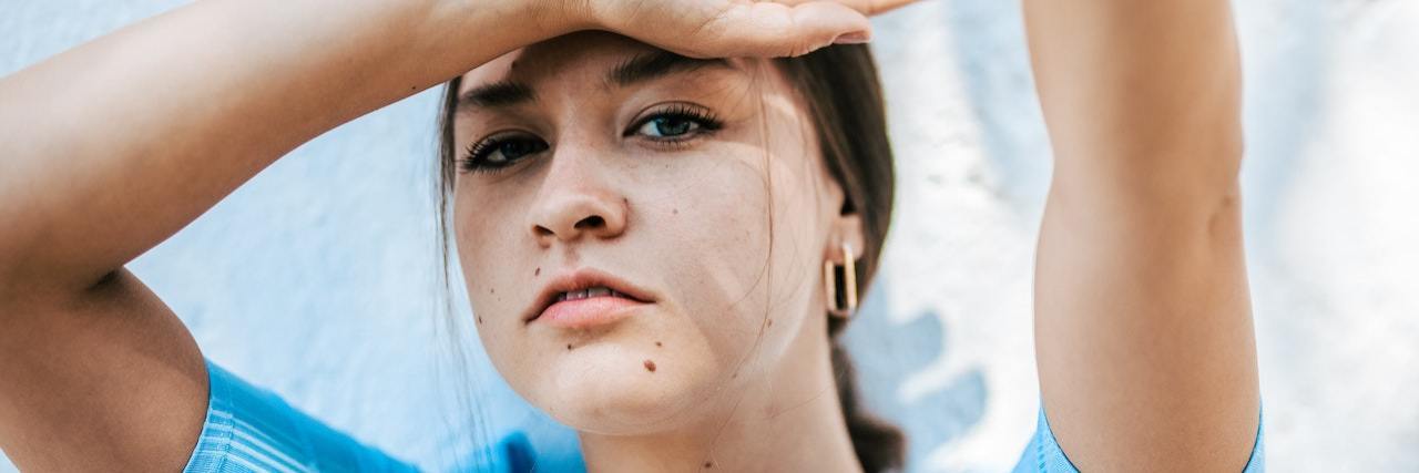 4 Fears I Have Because of My Chronic Illness A woman with one hand on her head, the other in the air