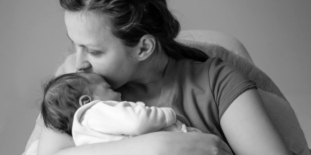 How Postpartum Rage Made Me Treat My Daughter black and white photo of a mother kissing her baby