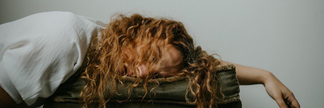 A woman leaning on a pillow with her hair in her face
