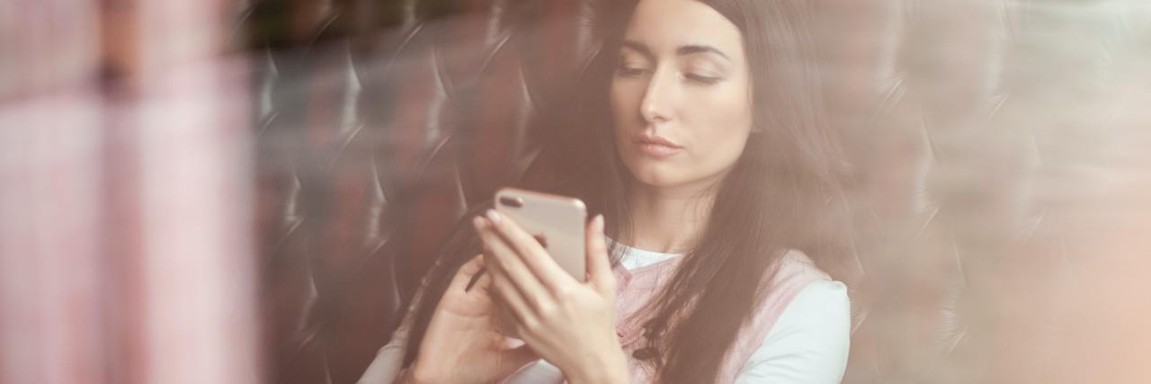 The Hidden Meanings Behind My Facebook Posts About Depression photo of woman on couch with a smartphone