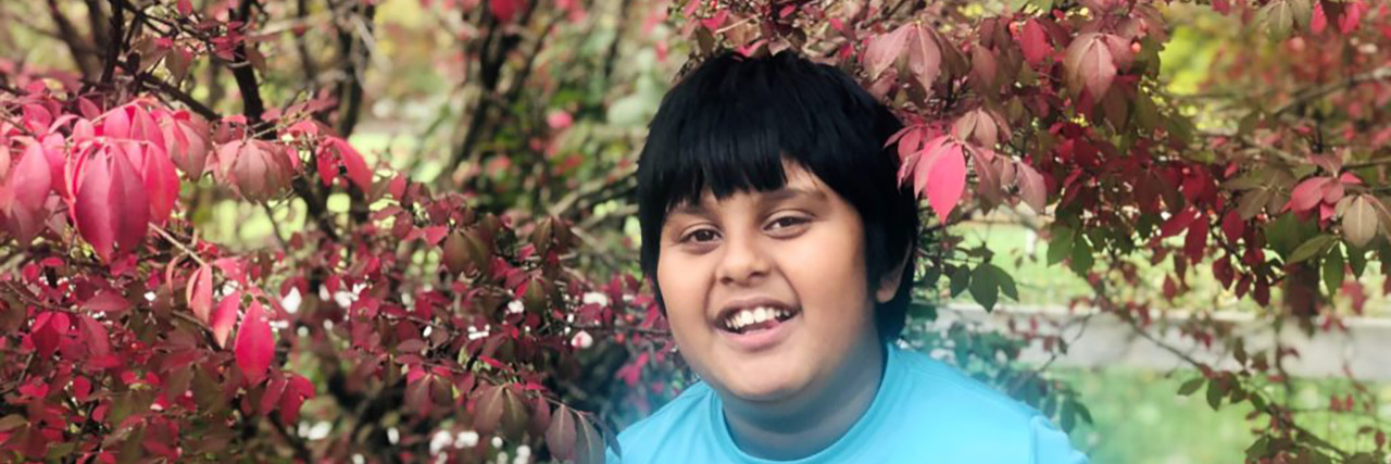 Finding a Different Kind of Happy as Parents of a Child With Autism Tulika's son standing by a tree with red leaves.