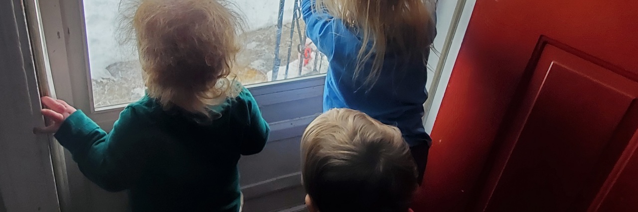 three young children looking out a window