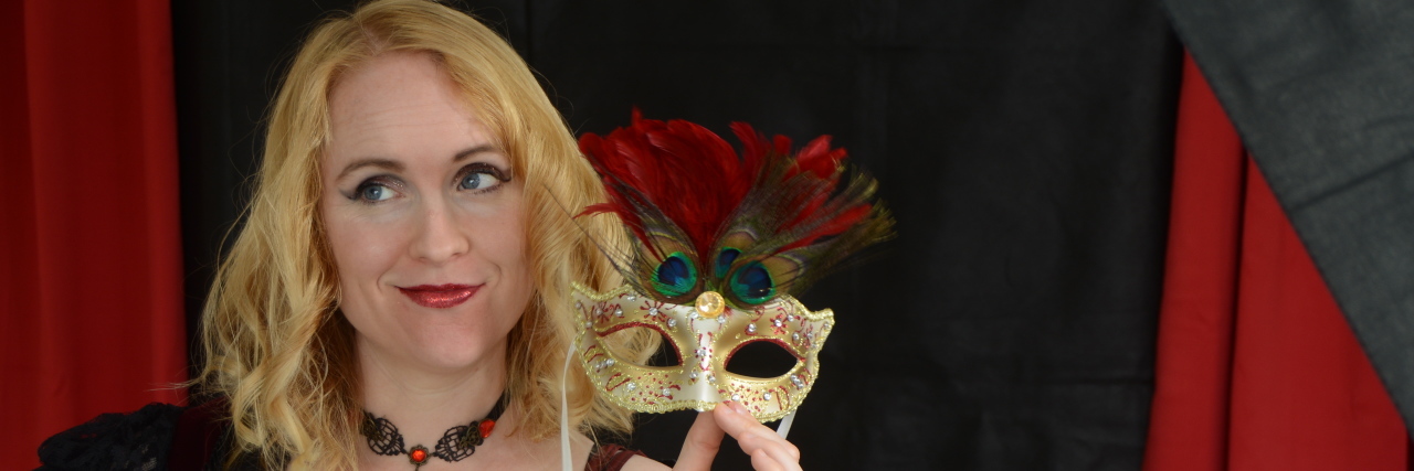 When I Realized I Was Apologizing for Being Autistic Louise holding a masquerade mask.