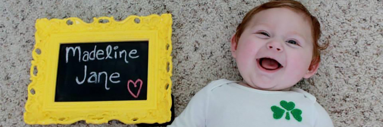 What This Yellow Chalkboard Taught Me After My Daughter's Birth Injury Madeline Jane next to the yellow-framed chalkboard bearing her name.
