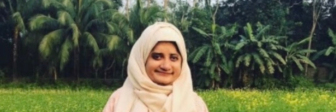My Journey to Become a Journalist With 22q Deletion Syndrome Amani wearing a pink dress and white head scarf, standing outside.