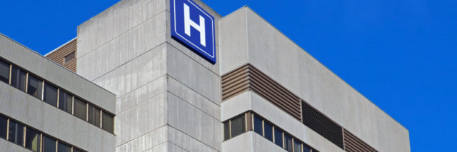 Large concrete building with H sign for hospital
