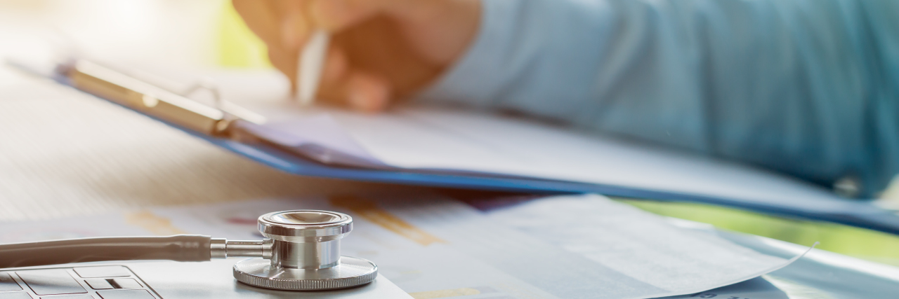 Doctor working in hospital writing on prescription clipboard.