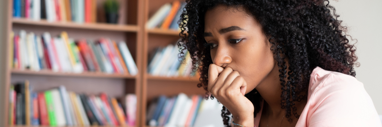 Intrusive Thoughts Made Me Think I Wanted To Harm People photo of woman looking upset with bookcases behind her