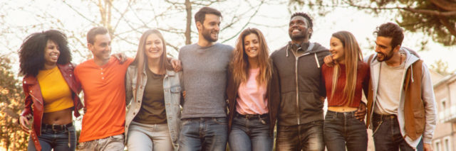 group of multiracial young adults with arms around each other smiling